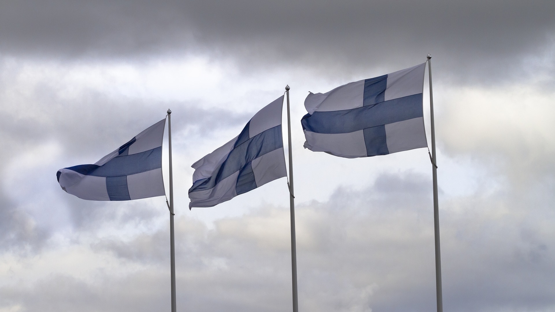 kolme suomen lippua liehuu lipputangoissa